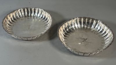 une paire de bols plaqués argent aux bords cannelés, posés sur une table