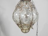 a glass light hanging from a chain on a wall