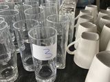 many glasses and cups on a table with a person in the background