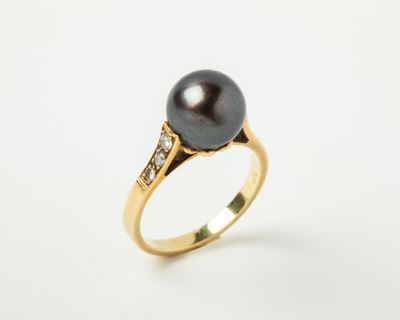 une bague en perle noire et diamants sur fond blanc