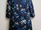 La robe est bleue et blanche, avec des fleurs bleues.