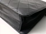 a close up of a black chanel bag on a white surface