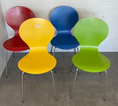 Quatre chaises colorées sont alignées contre un mur dans une pièce