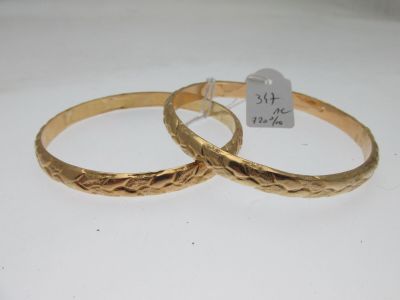 paire de bracelets de couleur dorée, ornés d'un motif gravé de chaque côté