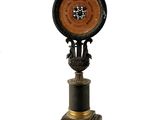 une horloge posée sur un socle, sur fond blanc