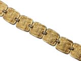 a close up of a gold bracelet on a white surface