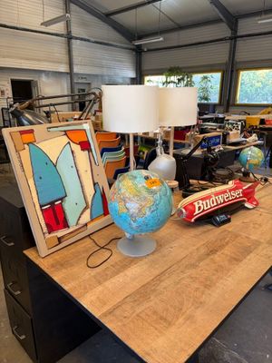 une table sur laquelle se trouvent une lampe, un globe terrestre et un tableau