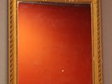 a mirror with a gold frame and a red wall