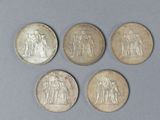 four different types of silver coins on a gray surface