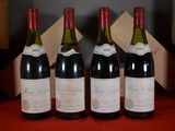 four bottles of wine are lined up on a red table