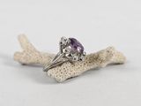 a close up of a ring with a purple stone on top of a piece of coral