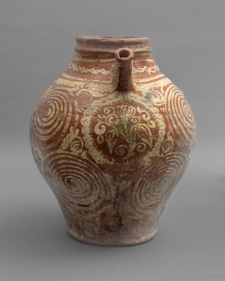 a brown and white vase sitting on a gray surface