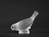 white glass bird sitting on top of a black surface