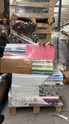une pile de livres posée sur une palette, à côté d'une pile de cartons