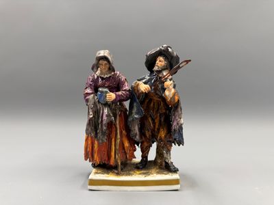 two figurines of two men dressed in costumes and hats