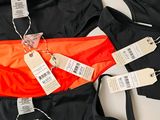 several tags hang on the back of an orange and black bathing suit