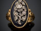 une bague en or sertie d'une pierre noire ovale, entourée de fleurs et de feuilles