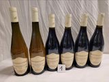 six bouteilles de vin sont alignées sur une table