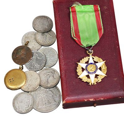 des pièces et une médaille se trouvent dans une boîte rouge ornée d'un ruban vert