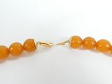 a close up of a yellow beaded necklace on a white surface