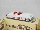 a white car sitting on top of a box next to a box of brown boxes