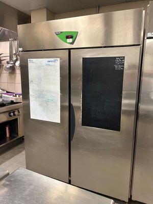 un grand réfrigérateur en acier inoxydable dans une cuisine dont la porte est ornée d'un tableau noir