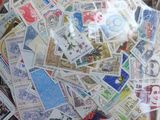 de nombreux timbres de toutes sortes dans un vase en verre posé sur la table