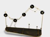 une sculpture noire et dorée surmontée de cinq lampes