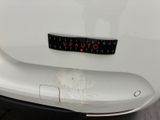 the rear end of a white car with a sticker on it ' s bumper