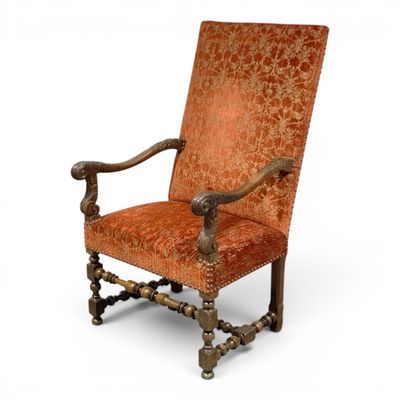 an orange upholstered chair with a wooden frame and ornate upholstered seat