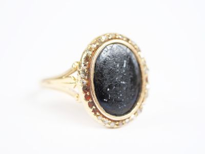 a close up of a gold ring with a black stone in it