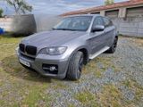 a picture of a silver bmw suv parked in front of a building