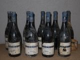 Six bouteilles de vin sont alignées sur une table devant un mur.