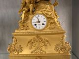 a gold clock that is on display in a glass case
