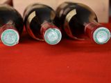 three bottles of wine are lined up on a red cloth