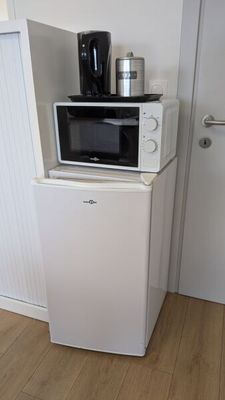 un petit réfrigérateur blanc surmonté d'un micro-ondes