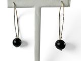 une paire de boucles d'oreilles ornées de perles noires, suspendues à un support blanc