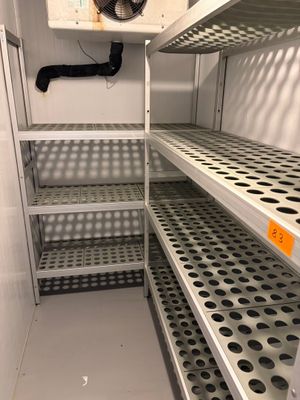 une étagère métallique surmontée d'un ventilateur, dans une pièce