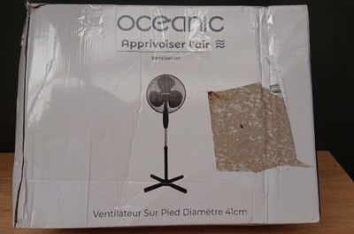 une boîte en carton sur laquelle est posé un ventilateur, posée sur une table