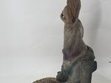 statue of a woman sitting on a chair with a cell phone in her hand