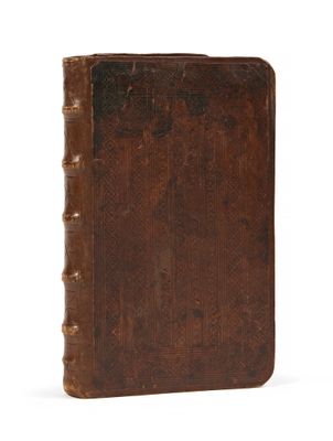 un vieux livre brun posé sur une surface blanche