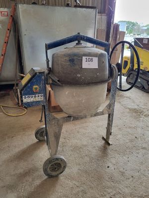 a cement mixer sitting in a garage next to other equipment