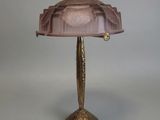 brass table lamp with a pink shade on top of it