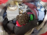 a bag full of clothes sitting on a bed