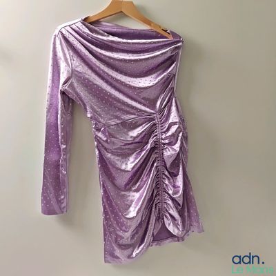 purple long sleeved dress hanging on a hanger against a wall