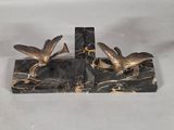 two birds that are sitting on a marble bookend