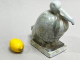 a statue of a pelican next to a lemon on a table