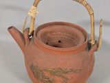 a brown tea pot with a bamboo handle on a table
