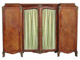 une armoire ancienne en bois à deux portes, ornée d'un rideau vert