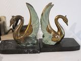 two statues of a swan and a dragon on a marble base